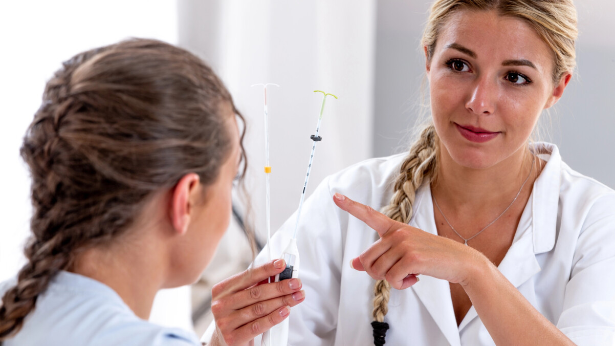 A healthcare professional showing intrauterine devices (IUDs), including the Mirena Coil, to a patient during a medical consultation.