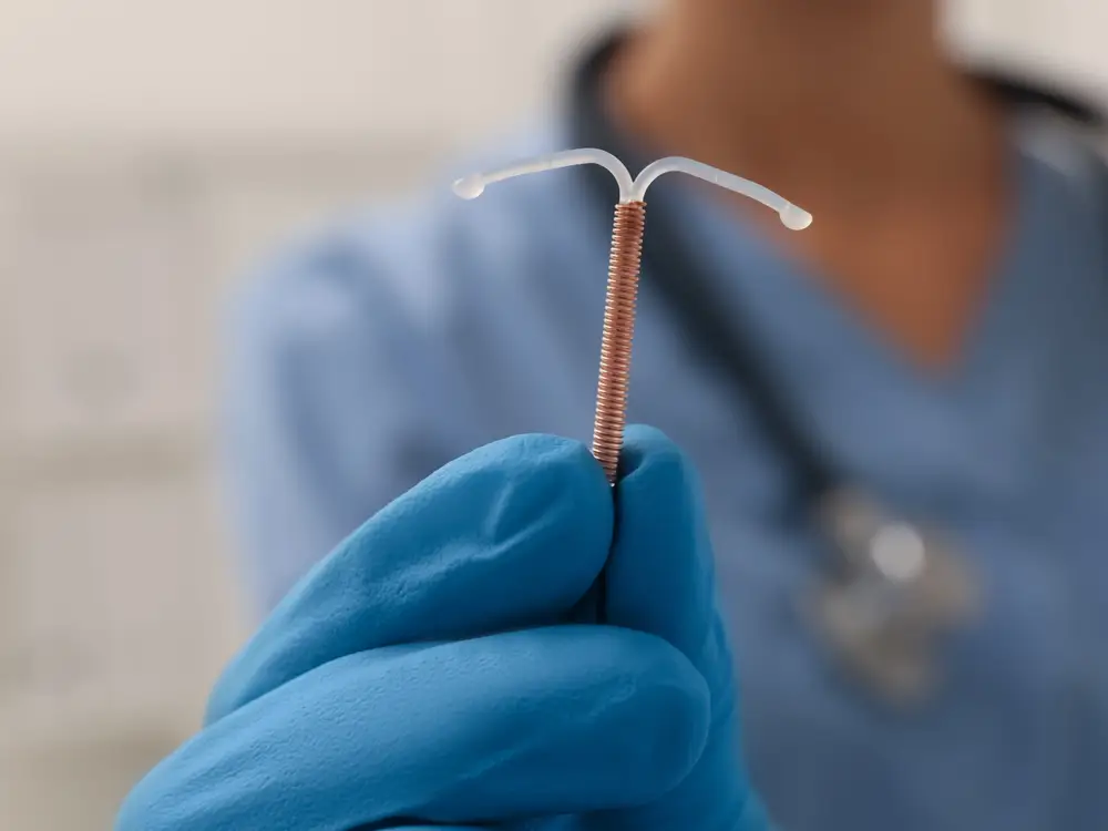 How an Intrauterine Coil (IUD) Can Help You Beyond Contraception 1 Doctor holding a copper contraceptive coil